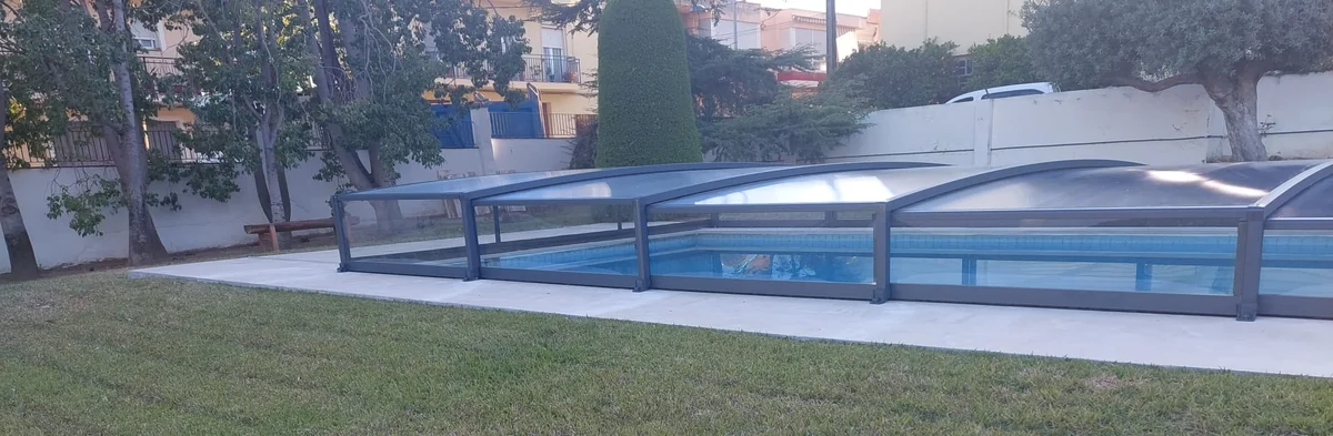 Agua limpia de la piscina vista a través de los paneles de una cubierta telescópica baja cerrada