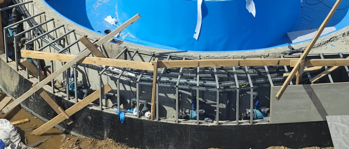 Piscina en construcción con las tuberías de la depuración a la vista entre el encofrado, antes de rellenar el perímetro