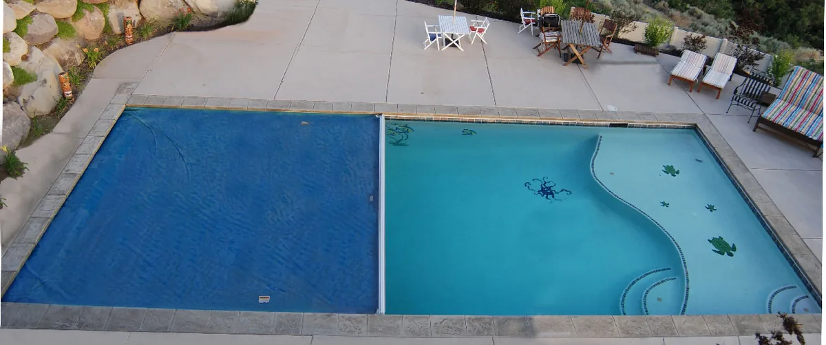 Piscina vista desde arriba con una cubierta automática de lona sobre guías laterales cerrada hasta la mitad del vaso