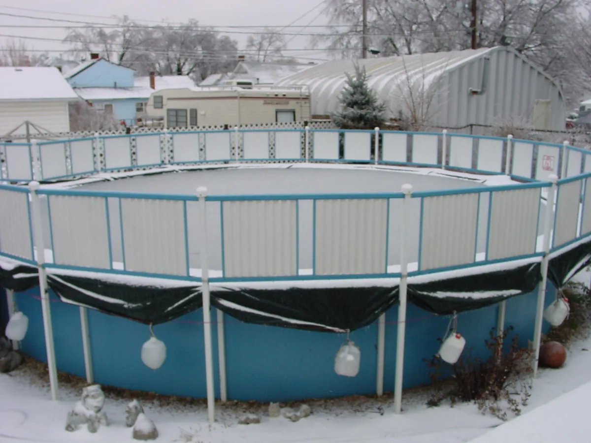 Piscina de acero redonda montada sobre el suelo en invierno, con la cubierta puesta y nieve alrededor