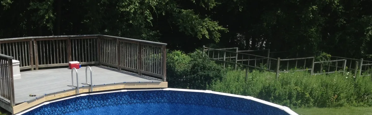 Piscina elevada redonda con liner azul junto a una tarima de madera con barandilla a la altura del borde