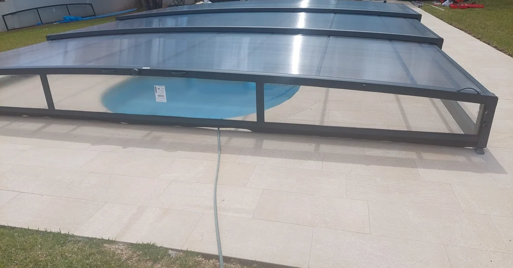 Primer módulo de una cubierta telescópica baja visto de cerca, con la zona semicircular de la piscina debajo