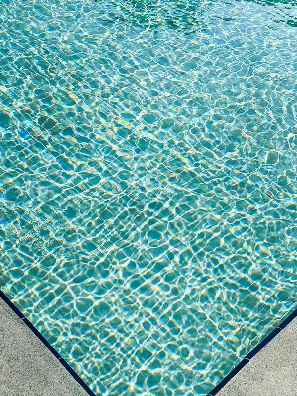 Borde de piscina con agua turquesa sobre gresite